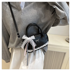 Detail of black mini Boston bag with lace bow decoration and silver butterfly metal part