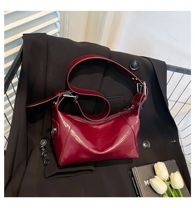 Detail of burgundy glossy patent leather underarm bag on a black blazer with flowers