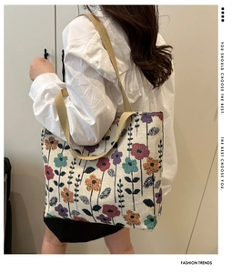 Detail of floral embroidery on cream canvas tote bag with woven shoulder strap