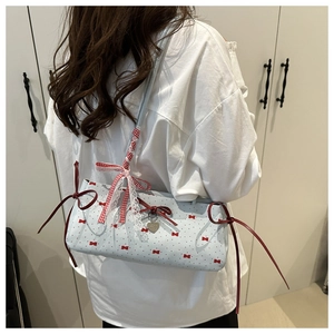 Detail of light blue polka dot shoulder bag with red bow accents and heart charm