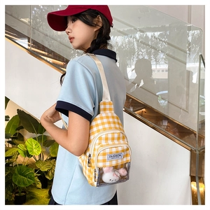 Detail of yellow checkered mini crossbody bag with a plush toy in a clear window pocket