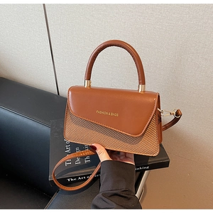 Detail of vintage brown leather flap and woven straw texture on the small crossbody bag