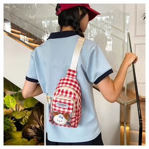 Close-up of red plaid crossbody bag featuring a clear PVC pocket and plush puppy charm