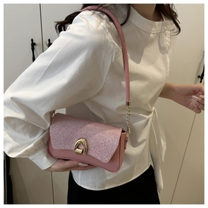 Close-up of pink glitter flap shoulder bag with golden horseshoe metal lock on model