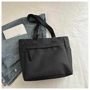 Detail of black woven tote bag with side pockets and stylish braided zipper puller