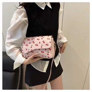 Detailed side view of pink crossbody bag with cherry patterns on a female model