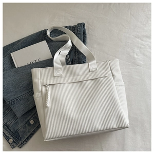 Detail view of white corduroy tote bag with front zipper pocket and woven rope puller