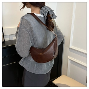 Deep brown half-moon hobo bag in vintage faux leather worn as a shoulder underarm bag