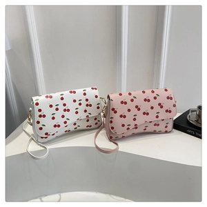 Close-up of cute cherry print pattern and gold metal clasp on white and pink PU bags