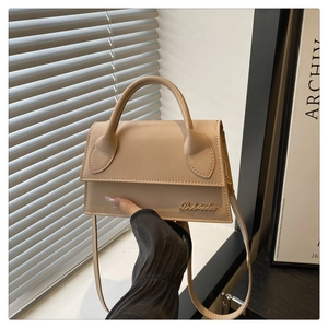 Chique beige crossbodytas met gouden logo op lederen flap in zacht natuurlijk licht