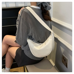Detail of a white minimalist half-moon shoulder bag in smooth leather finish