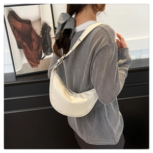 Model wearing a white faux leather crescent bag with adjustable shoulder strap