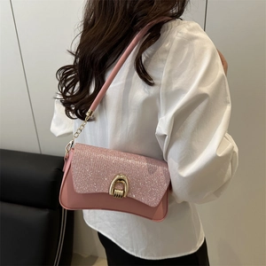 Pink sequin underarm bag with gold horseshoe buckle and chain strap shown on model