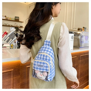 Detail of blue plaid crossbody bag with a transparent window pocket and plush bear toy
