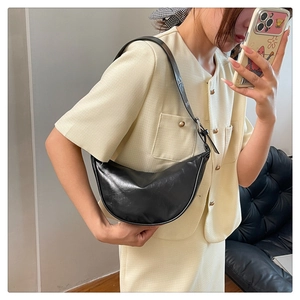 Detail of black leather crescent bag shoulder strap with silver buckle and logo embossing