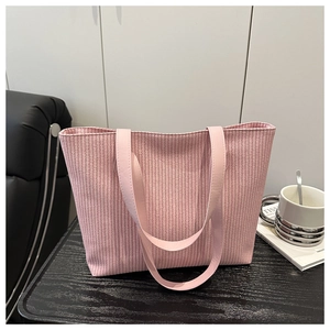 Detail of pink woven tote bag with smooth shoulder straps on dark wooden surface