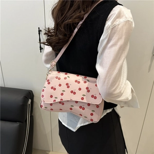 Pink crossbody bag with red cherry print featuring a curved flap for a trendy summer look