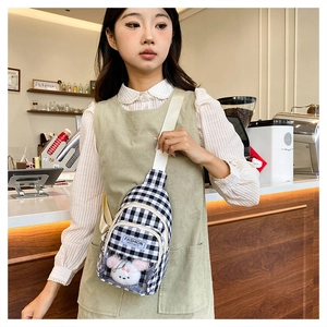 Detail of checkered crossbody bag with transparent PVC pocket and cute plush toy