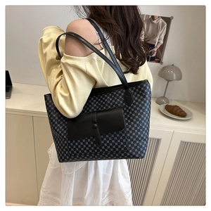 Polka dot tote bag with black leather straps and front pocket shown on a model