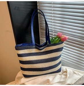 Detail of striped woven tote bag with blue handles and decorative tulips inside