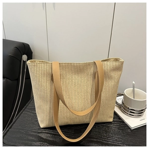 Detail of light beige woven tote bag showing tight straw texture and brown leather handles