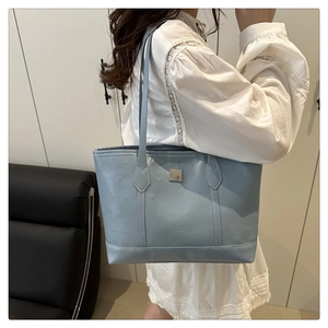Detail view of light blue tote bag featuring embossed heart patterns and metallic plaque
