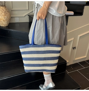 Close-up of blue and white striped woven tote bag with durable navy blue handle