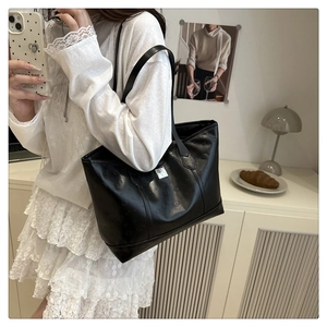 Close-up of black tote bag featuring elegant floral embossed patterns and slim leather straps