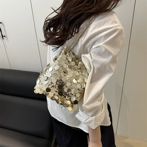 Silver sequin bucket bag with metal chain straps shown on a model in a minimalist setting