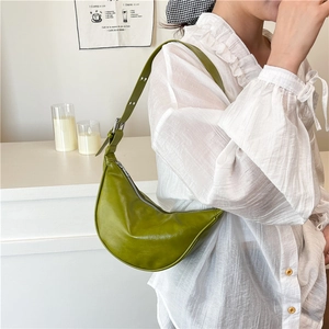 Chic olive green crescent shoulder bag in soft leather with adjustable strap shown on person