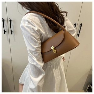 Detailed close-up of brown leather baguette bag featuring a stylish gold metal buckle