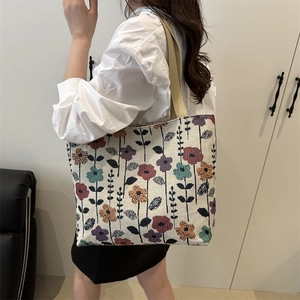 Large floral canvas tote bag with woven straps shown on shoulder for daily commute