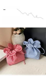 Detail of red and blue gingham drawstring bucket bags with floral petal-like top closure