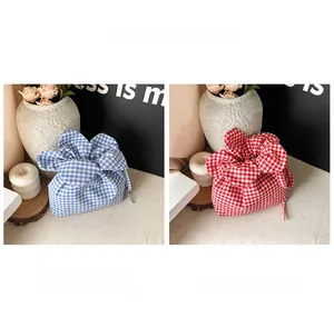 Detailed view of red and blue checkered cotton fabric drawstring bags with ruffle trim