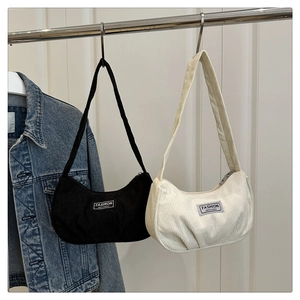 Detail of vintage corduroy underarm bags in black and beige with fashion logo tags