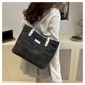 Close-up of textured grey tote bag with silver leather shoulder straps worn by model
