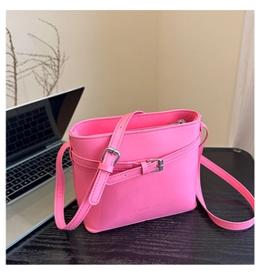 Detail of vibrant neon pink bucket bag featuring silver buckle and embossed logo detail