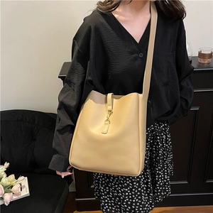 Classic beige faux leather bucket bag with gold metal clasp closure and adjustable strap