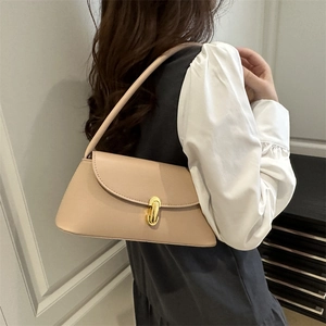 Minimalist beige leather baguette bag with gold metal buckle shown on a model