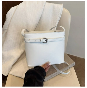Vue détaillée du sac seau blanc avec sangle à boucle et logo de marque gravé