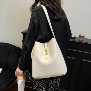 Creamy white textured leather bucket bag with gold hardware shown on model shoulder
