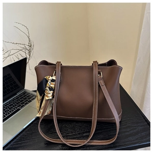 Detail of a brown leather tote bag with white contrast stitching and floral silk scarf