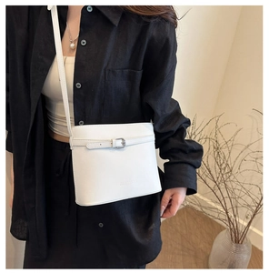 Détail de la sangle décorative, de la boucle et du logo embossé sur le sac seau blanc