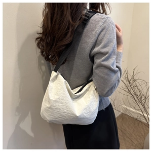 Minimalist white crescent dumpling crossbody bag with adjustable black shoulder strap and zipper