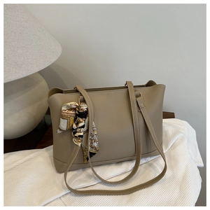 Detail of khaki PU tote bag featuring a decorative silk scarf wrapped around the handle