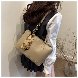 Detail of beige tote bag with vintage chain print silk scarf accessory on model shoulder