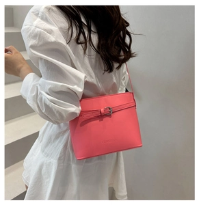 Detail view of the pink bucket bag with embossed logo and decorative buckle strap