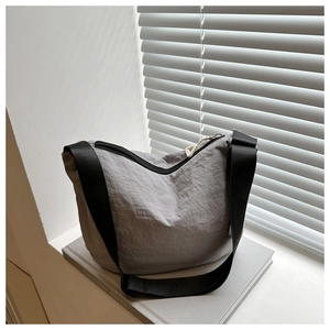 Detail of light grey nylon dumpling bag with black zipper and wide shoulder strap