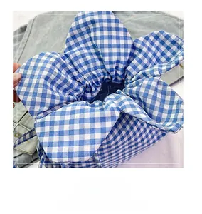 Detail view of a blue and white gingham drawstring bucket bag with a flower shape top
