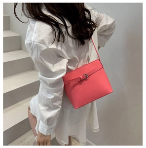 Gros plan d'un sac seau rose vif avec bride décorative et logo sur un mannequin